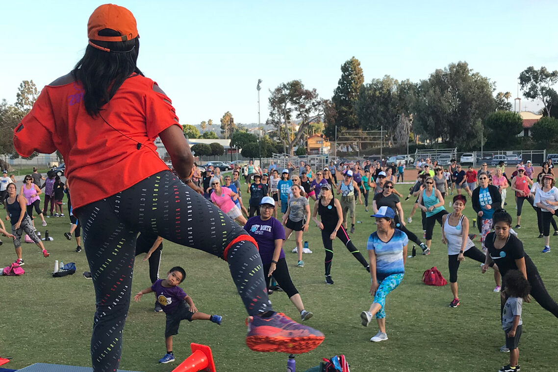 Zumba instructor is facing the field with participants following the instructor's dance movements.
