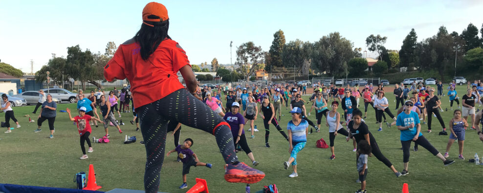 Zumba instructor is facing the field with participants following the instructor's dance movements.